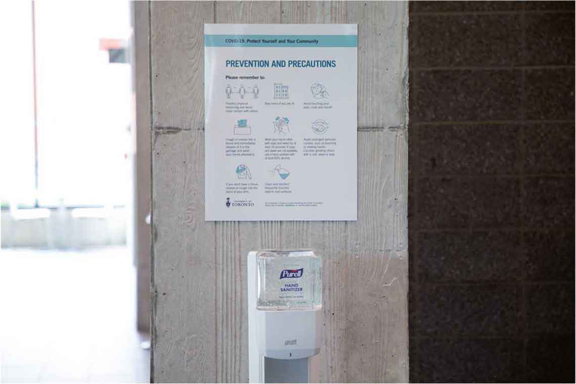 （写真１）エレベーター近くに設置されているハンドサニタイザーステーションとCOVID-19感染防止対策ポスター