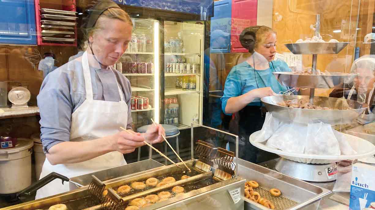 スナック売り場で黙々とドーナッツを揚げるメノナイトの女性